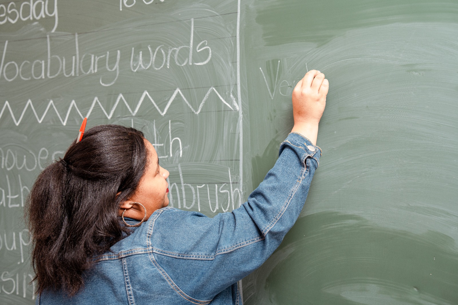 A teacher writing vocabulary words on the chalkboard